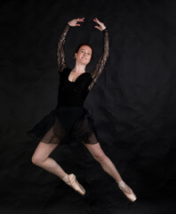 Beautiful dancer studio portrait jumping on black background.