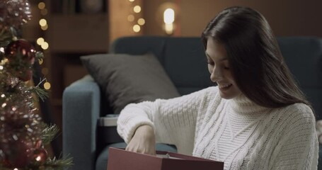 Young woman opening a christmas gift. - Powered by Adobe