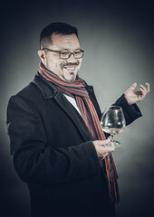 Solid cheerful man in coat and kerchief standing with glass of wine