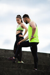 Sports young couple in sportswear having rest during workout outdoor on stairs