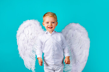 Child angel. Cute baby boy with white feather angel wings on blue background. Valentines day cupid...