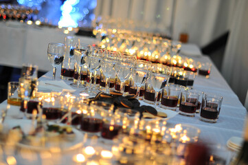 many different glasses and glasses with drinks on a white table with candles
