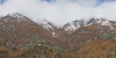Picturesque mountain landscape in Naturns in South Tyrol in autumn, in the background the snow-covered mountains, blue sky with clouds, no people