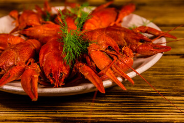 Plate with boiled crayfishes on wooden table