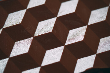 Macro shooting of a milk or dark chocolate tile with a shadow.