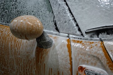 The car body is covered with soap suds to remove dirt. Car wash