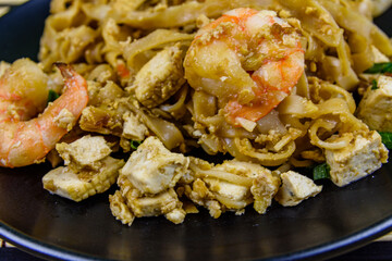 Black plate with pad thai on a bamboo mat