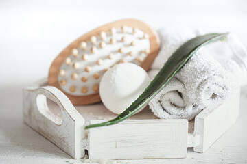 Spa composition with massage brush and bath bomb on light background close up.