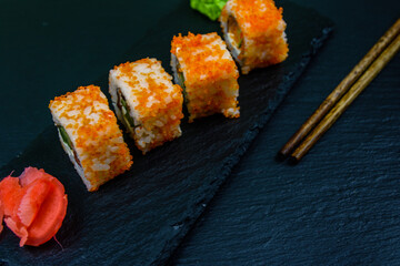 Sushi roll philadelphia with salmon, rice, cheese, cucumber, avocado and caviar on a slate board. Japanese food