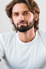 Obraz premium Man looking at self in mirror touching facial stubble. Masculine man in his 30s skincare beauty morning facial skin care healthy ageing routine in bathroom.