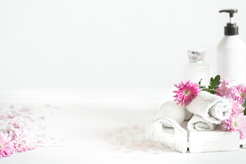 Spa composition with body care products and flowers on a light background copy space.