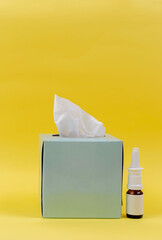 Nasal spray and paper napkins in a blue box on a yellow background. Medicine. Disease. Cold....
