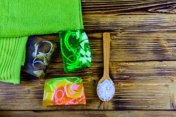 Fototapeta na wymiar Pieces of the handmade soap, towel and spoon with sea salt on wooden background. Top view