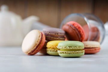 Colorful macarons on white table and wooden background