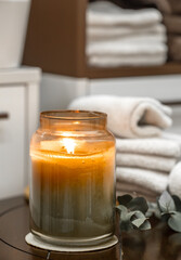 Spa composition with burning candle and bath towels close up.