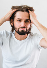 Close up of a cute young man messing with his hair. Skin Care.