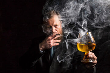 Solid confident bearded man in suit with glass of whisky and cigar with fume