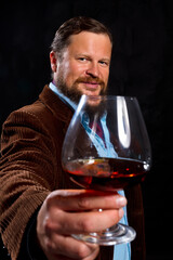 Stylish bearded man dressed in brown jacket with glass of whisky