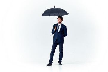 elegant gentleman with a dark umbrella on a light background and a classic suit