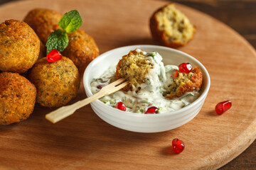 Falafel in tahini sauce close-up on a round wooden Board. National cuisine, street food