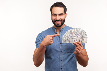 Happy bearded businessman in blue shirt pointing finger at dollar cash in his hand, looking at...
