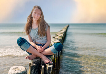 auf den Buhnen – junges Teenager Mädchen sitzt auf den  Buhnen am Ostseestrand 