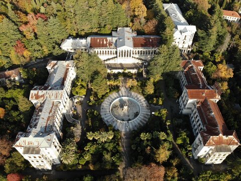 Aerial view of an old abandoned castle in the forest with a large dry fountain.