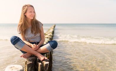 auf den Buhnen – junges Teenager Mädchen sitzt auf den  Buhnen am Ostseestrand 