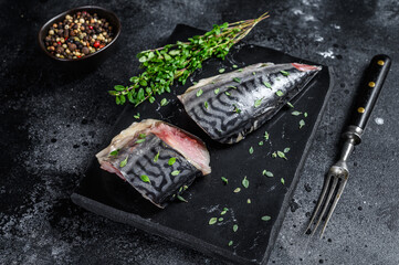 Cold smoked mackerel fish with herbs. Black background. Top view