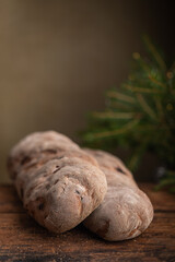 Rye bread with raisins on a wooden table, Vörtbröd Rye bread with raisins on a wooden table. With pinaceae branches in the background. Swedish traditional christmas bread wort bread or wort loaf.
