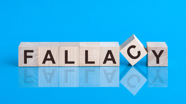 the text FALLACY is written on the cubes in black letters, the cubes are located on a blue glass surface