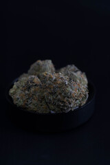 weed buds sitting in a black cap on black copy space