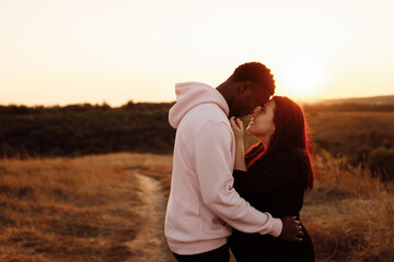 Handsome African American man gently hug beautiful white woman at sunset at the field, adorable lady smiling, enjoy tender moments, weekends outdoors, mixed race couple concept