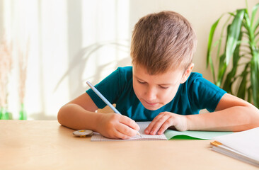 7 years old child boy doing math exercise while sitting at desk. Concept of homeschooling