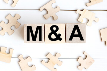 The word mergers and acquisitions is written in a wooden cube near WOODEN PUZZLES