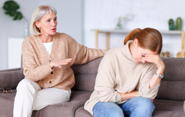 Mother and daughter having argument on sofa.