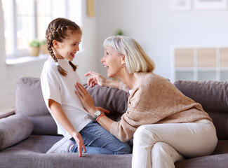 Grandmother playing with granddaughter on couch.