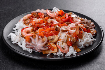 Tasty rice noodles with tomato, red pepper, mushrooms and seafood