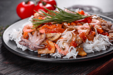 Tasty rice noodles with tomato, red pepper, mushrooms and seafood