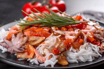 Tasty rice noodles with tomato, red pepper, mushrooms and seafood