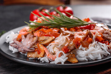 Tasty rice noodles with tomato, red pepper, mushrooms and seafood