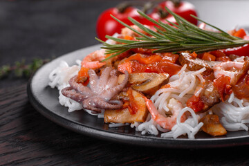 Tasty rice noodles with tomato, red pepper, mushrooms and seafood