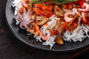 Tasty rice noodles with tomato, red pepper, mushrooms and seafood