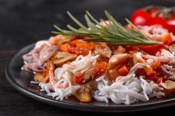 Tasty rice noodles with tomato, red pepper, mushrooms and seafood