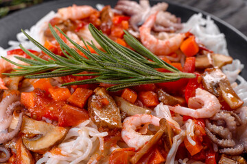 Tasty rice noodles with tomato, red pepper, mushrooms and seafood