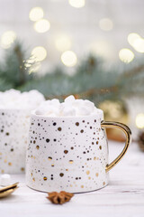 Obraz na płótnie Canvas White cup of cappuccino or cocoa with christmas tree on the buckground of gold bokeh, New Year drink