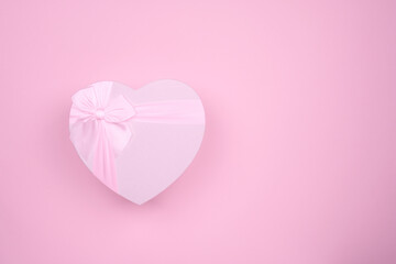 Pink big heart-shaped gift with bow for Valentine's Day on a pink background, minimalism