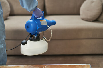 Worker disinfection near the couch in the apartment