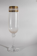 glass with golden ornament on white table casts shadow