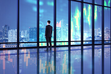 Fototapeta na wymiar Businessman standing in office interior with glowing stock charts.